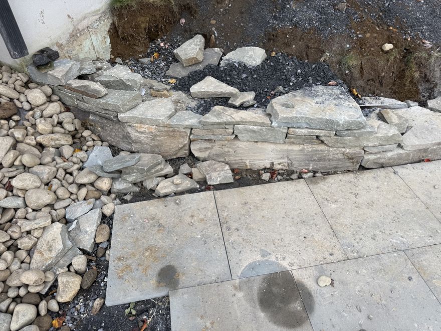 Stone wall meeting a bluestone walkway